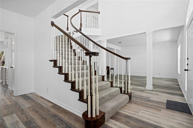 stairway with wood-type flooring and decorative columns