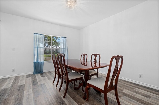 dining space featuring wood-type flooring and a notable chandelier