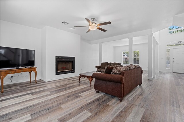 living room featuring decorative columns, ceiling fan, and light hardwood / wood-style floors