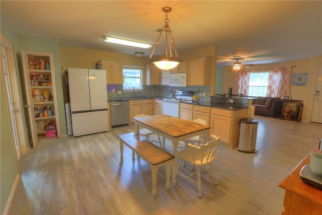 kitchen featuring white appliances, dark countertops, plenty of natural light, and a sink
