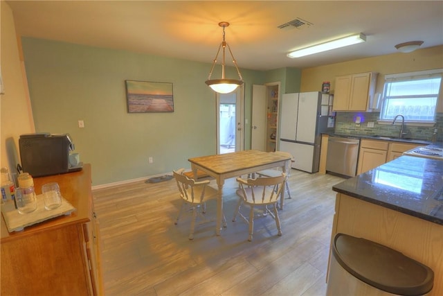 kitchen featuring stainless steel dishwasher, freestanding refrigerator, visible vents, dark countertops, and a sink