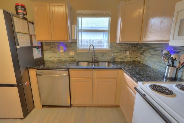 kitchen with backsplash, appliances with stainless steel finishes, a sink, and dark stone countertops