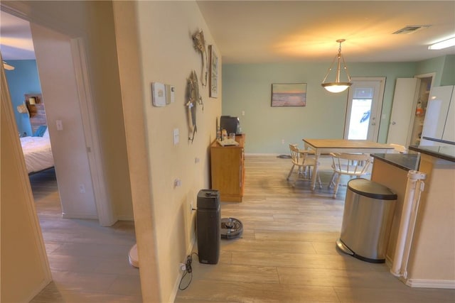 hall featuring visible vents, light wood-style floors, and baseboards