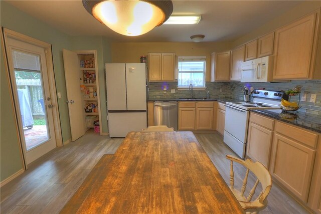 kitchen with white appliances, light wood-style floors, tasteful backsplash, a sink, and wood counters