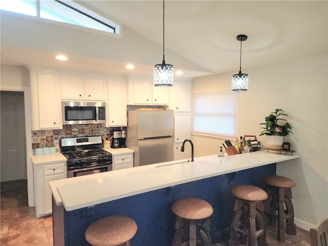 kitchen featuring vaulted ceiling, sink, white cabinetry, appliances with stainless steel finishes, and decorative light fixtures