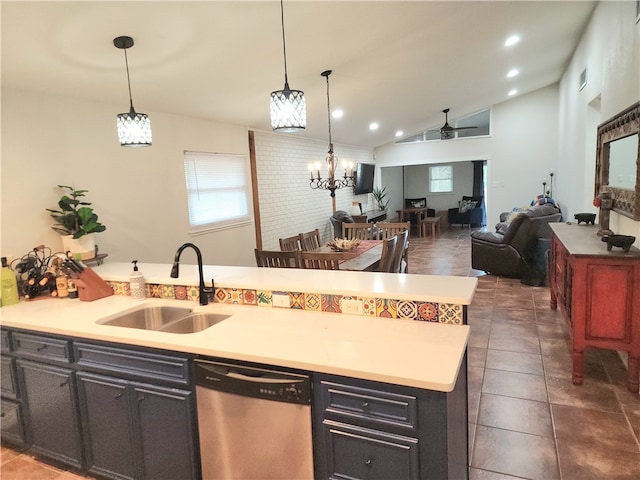 kitchen featuring sink, stainless steel dishwasher, lofted ceiling, pendant lighting, and dark tile patterned flooring