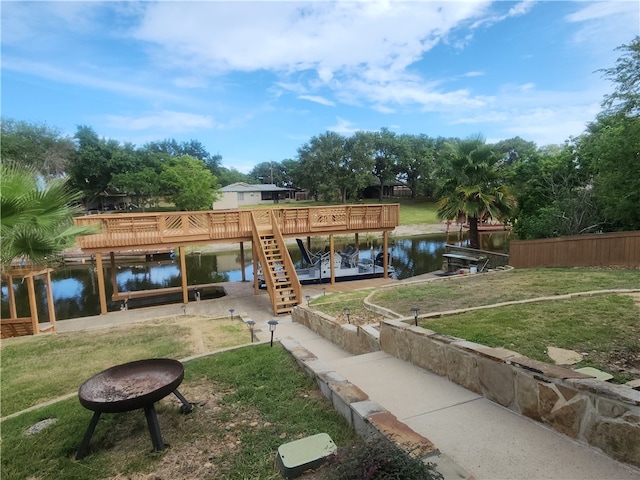 surrounding community with a dock, a deck with water view, and a lawn