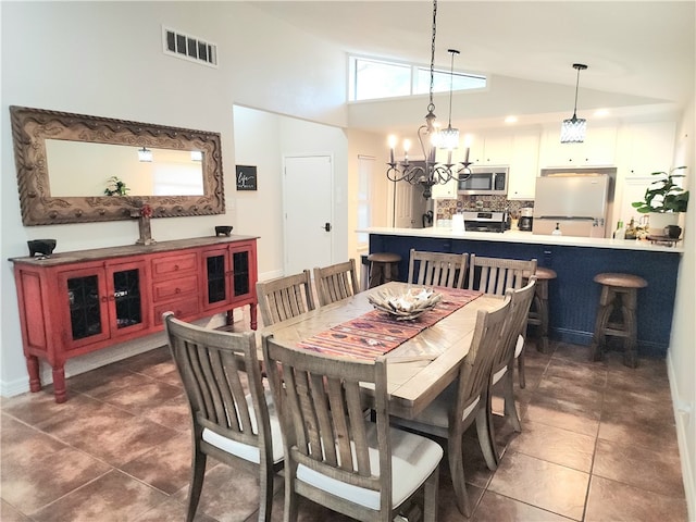 tiled dining area featuring high vaulted ceiling and a chandelier