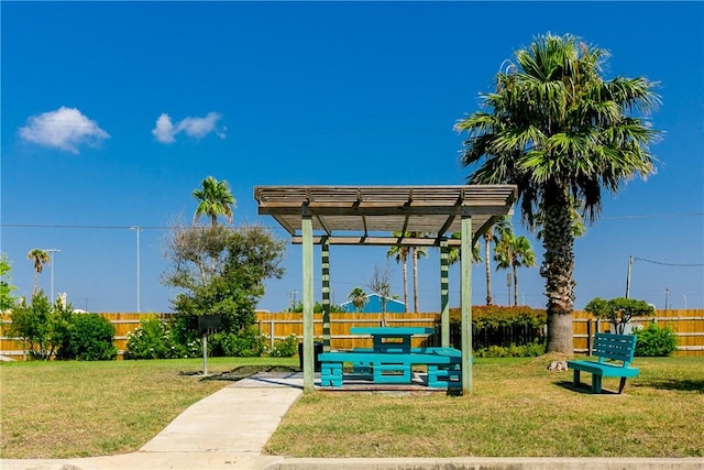 view of property's community featuring a lawn, fence, and a pergola