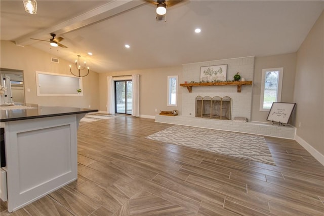 unfurnished living room with lofted ceiling with beams, plenty of natural light, wood tiled floor, and a fireplace