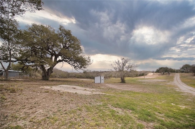 view of yard featuring an outbuilding, a storage unit, and a rural view