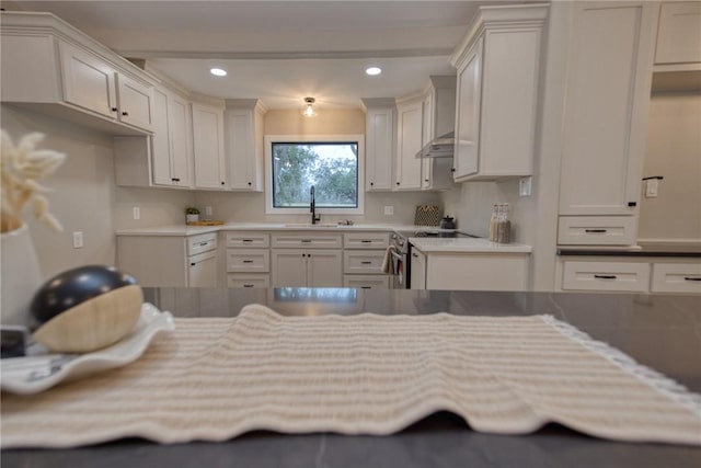 kitchen featuring electric range, white cabinets, wall chimney range hood, a sink, and recessed lighting