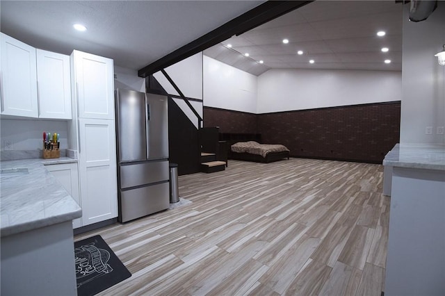 interior space with light stone countertops, white cabinets, and freestanding refrigerator