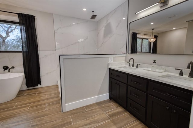 full bathroom featuring a wealth of natural light, wood tiled floor, and a sink