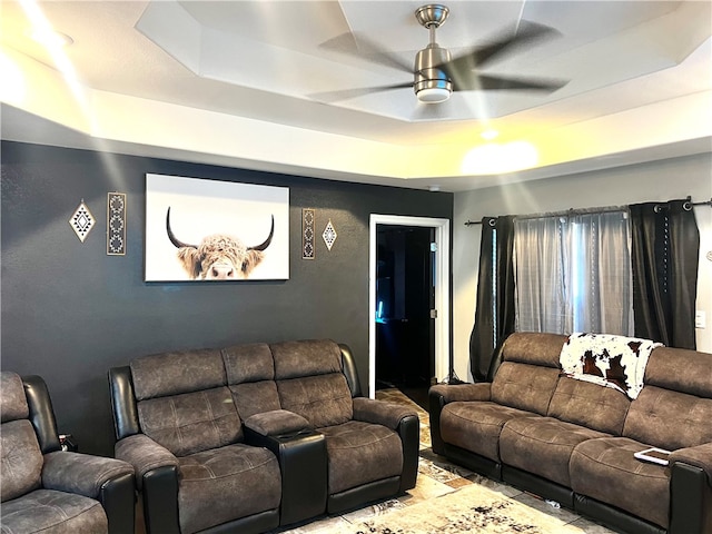 living room featuring ceiling fan and a tray ceiling