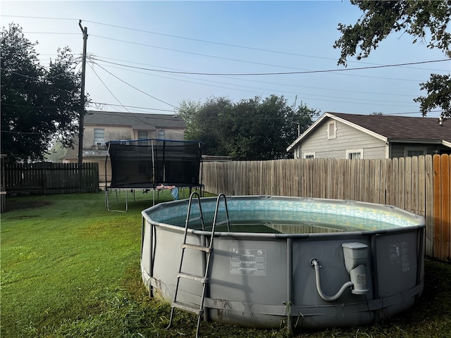 view of pool featuring a yard and a trampoline