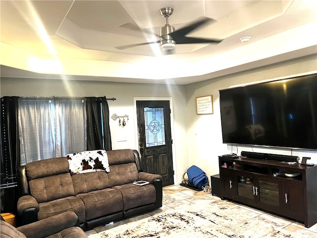 living room with ceiling fan and a raised ceiling