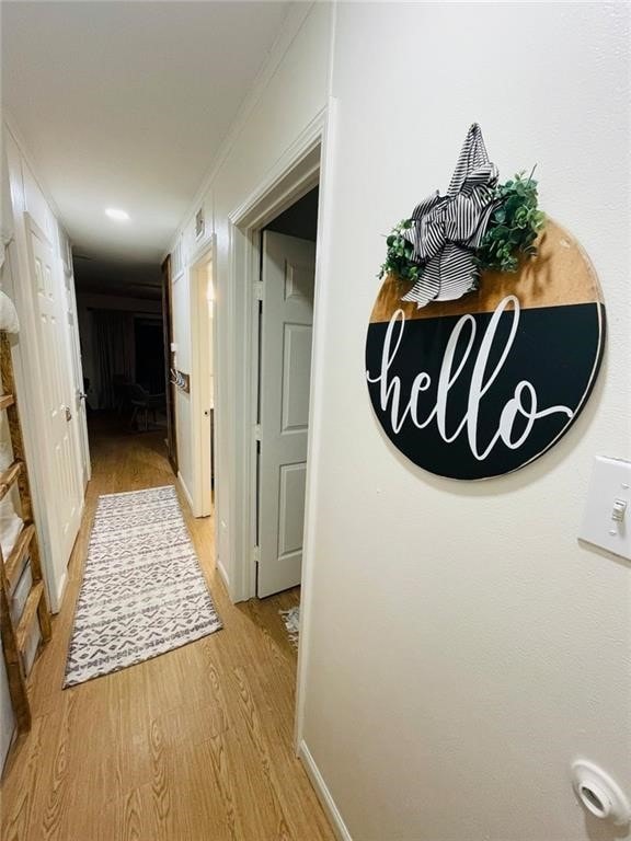 hallway with light wood-type flooring and ornamental molding