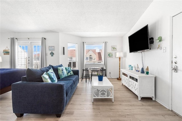 living room featuring a textured ceiling, light hardwood / wood-style floors, and french doors