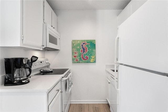 kitchen with white cabinetry, light wood-type flooring, a textured ceiling, and white appliances