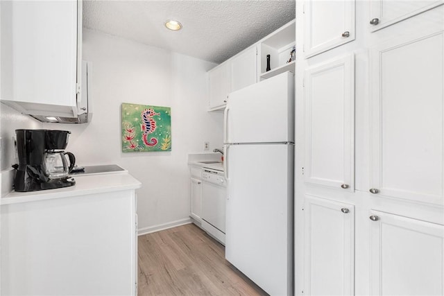 kitchen with white appliances, light hardwood / wood-style flooring, a textured ceiling, and white cabinets