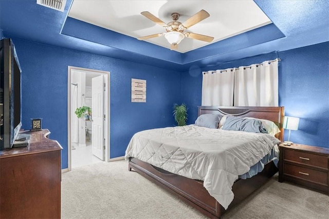 bedroom with baseboards, a tray ceiling, visible vents, and light colored carpet