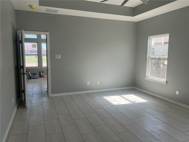 empty room featuring baseboards, visible vents, and ceiling fan