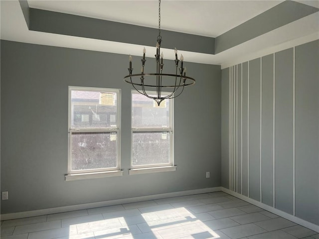 unfurnished dining area featuring a chandelier and baseboards