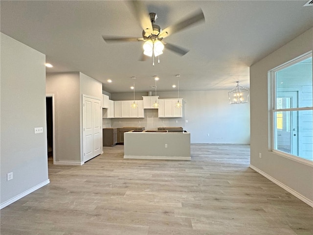 kitchen featuring decorative light fixtures, white cabinetry, ceiling fan with notable chandelier, a kitchen island, and light hardwood / wood-style floors