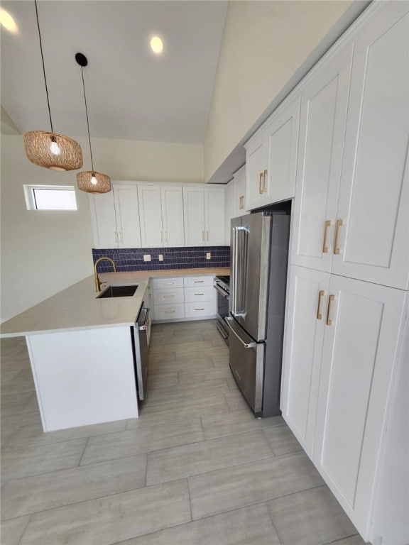kitchen with decorative backsplash, white cabinets, a sink, appliances with stainless steel finishes, and light countertops