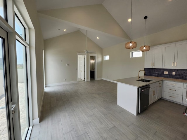 kitchen featuring a sink, black dishwasher, high vaulted ceiling, a peninsula, and white cabinetry