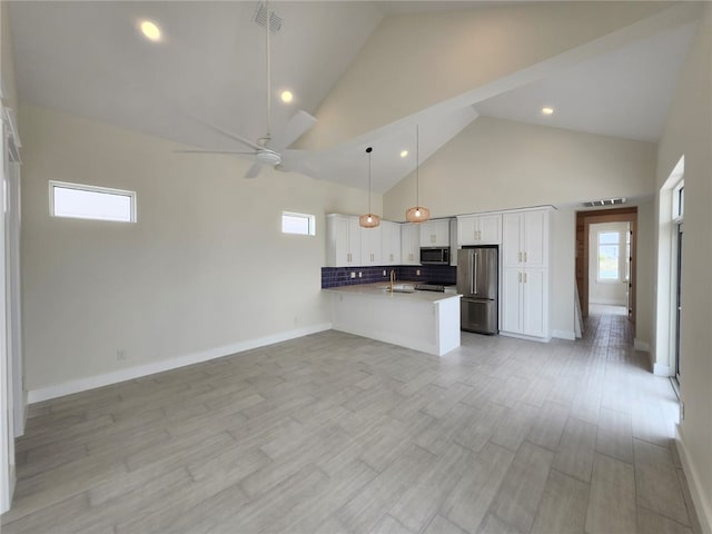 kitchen with stainless steel appliances, high vaulted ceiling, a peninsula, white cabinets, and open floor plan