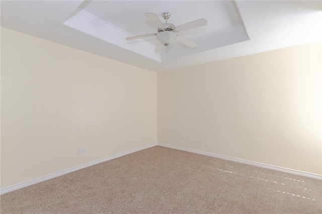 carpeted spare room with ceiling fan and a tray ceiling