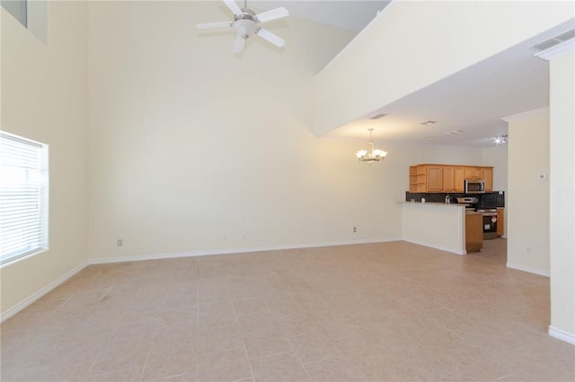 unfurnished living room with ceiling fan with notable chandelier and a high ceiling