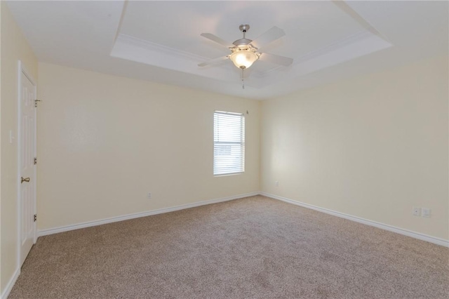 empty room with carpet, ceiling fan, and a raised ceiling