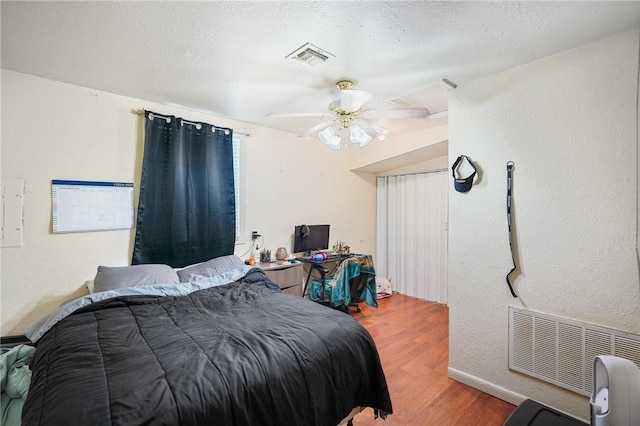 bedroom with hardwood / wood-style floors, a textured ceiling, and ceiling fan