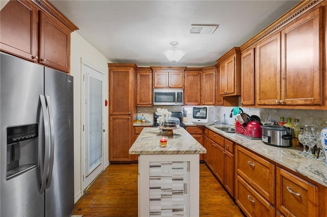 kitchen with dark wood-type flooring, appliances with stainless steel finishes, a center island, and backsplash