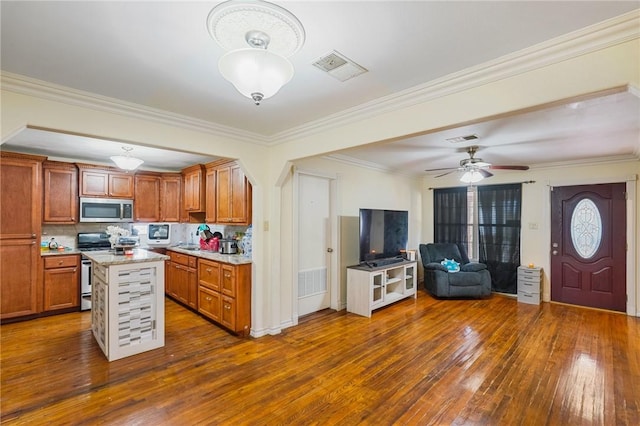 kitchen with tasteful backsplash, light stone counters, dark hardwood / wood-style floors, a kitchen island, and stainless steel appliances