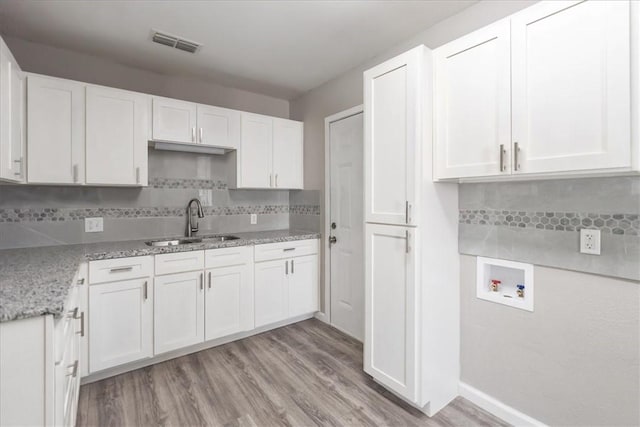 1337 Daytona Dr, Corpus Christi, TX 78415 - kitchen featuring a sink, white cabinets, decorative backsplash, and light wood finished floors