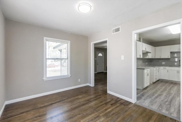 1337 Daytona Dr, Corpus Christi, TX 78415 - kitchen with dark wood-type flooring, baseboards, white cabinets, and light countertops