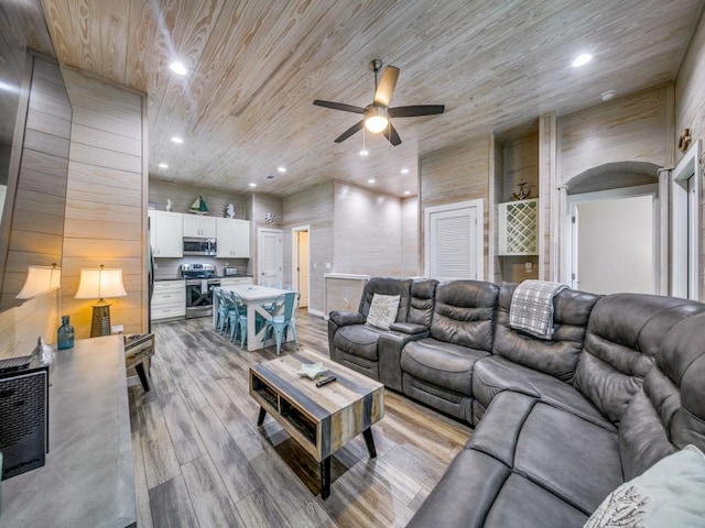 living room with wooden ceiling, light hardwood / wood-style flooring, wooden walls, and ceiling fan