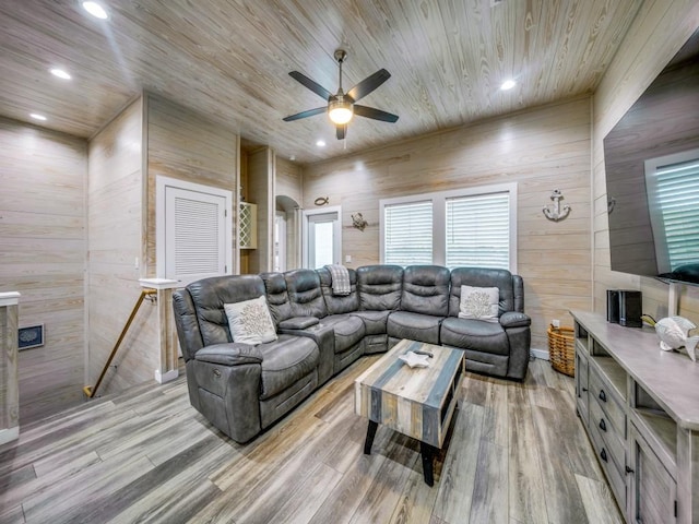 living room with ceiling fan, wood walls, light hardwood / wood-style floors, and wooden ceiling