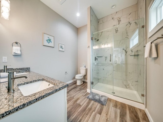 bathroom featuring hardwood / wood-style flooring, toilet, a shower with shower door, and vanity