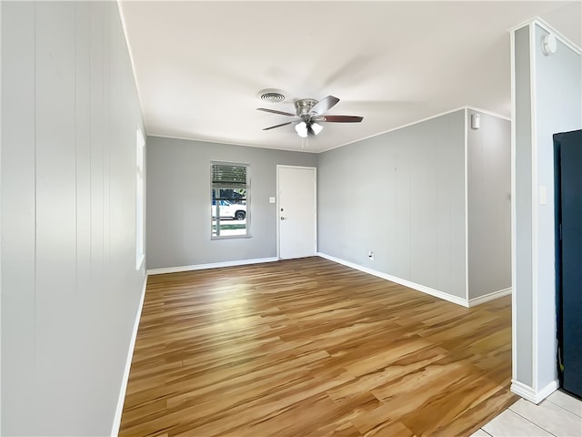 empty room with ceiling fan, wooden walls, and light hardwood / wood-style flooring