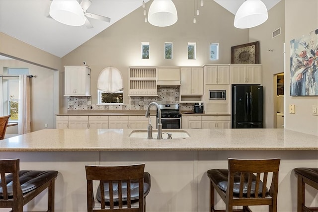 kitchen featuring sink, a breakfast bar area, backsplash, appliances with stainless steel finishes, and decorative light fixtures