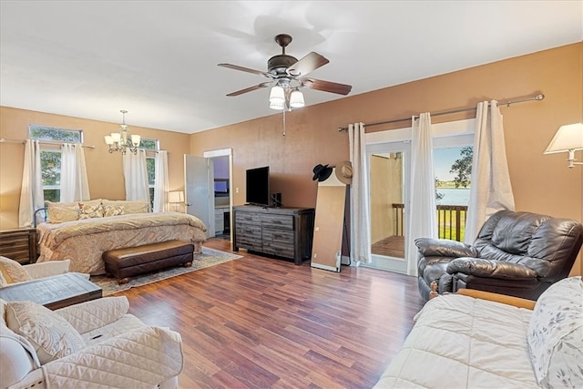 bedroom featuring dark wood-type flooring, ceiling fan with notable chandelier, and access to outside