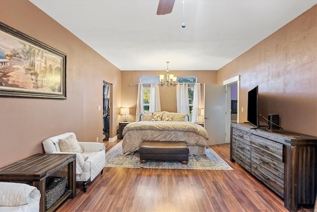 bedroom with wood-type flooring and ceiling fan with notable chandelier