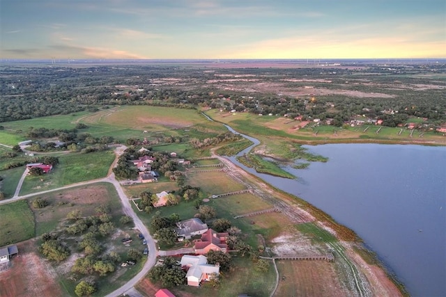 aerial view at dusk featuring a water view and a rural view