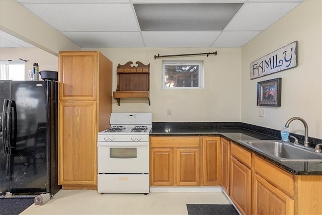 kitchen with black fridge, kitchen peninsula, sink, a drop ceiling, and white gas stove