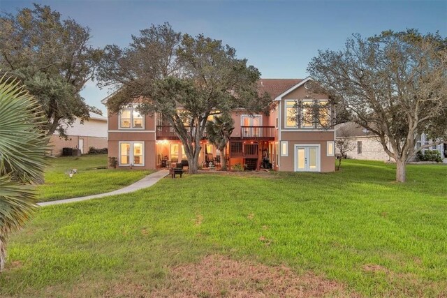 24475 La Ponderosa Dr, Mathis, TX 78368 - back of property featuring french doors, a deck, a yard, and stucco siding